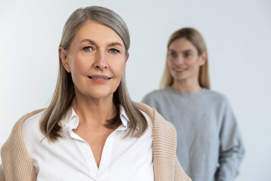 Confident mature woman standing, her daughter behind her