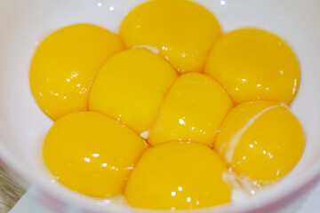 Yellow fresh egg yolks in white plate for cooking, close up view