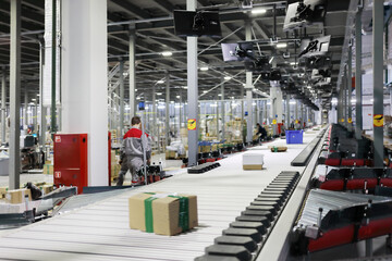 People work in modern workshop with conveyor, many displays in warehouse