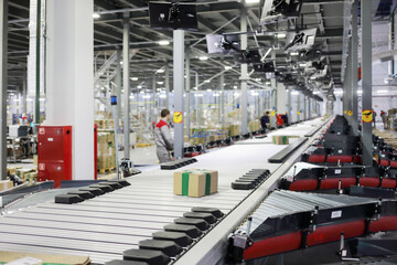 Workers in modern workshop with conveyor, many displays in warehouse