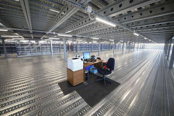 Workplace with computer in warehouse with many shelves - big hall in sorting center