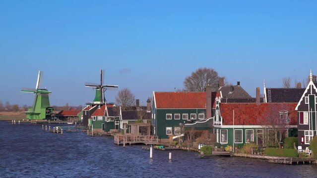 Beautiful Dutch scenery panorama of Zaanse Schans village in Netherlands in spring time. Ancient windmills at the Zaan river against a blue sky in sunny weather