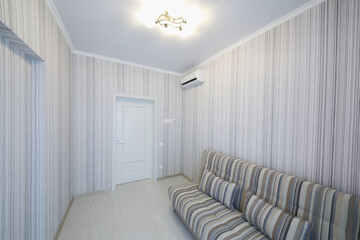 Empty simple cozy room striped walls and striped sofa, air conditioner