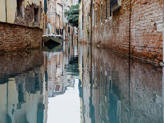 Canal in Venice with old stone walls and a single boat