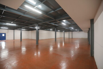 empty warehouse filled with pharma blue container rack for storage and epoxy flooring in...