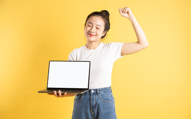 Portrait of Asian woman using computer and  posing on yellow background