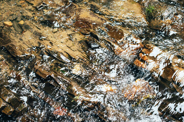 Abstract nature textured background, water waves in the lake with sun reflection, clear transparent water. Image of water in mountain river