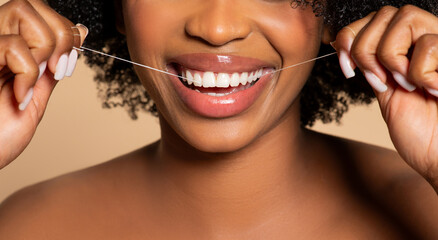 Close-up of black woman flossing, showcasing healthy teeth
