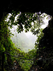 One of the caves on the levadas of Madeira. Beautiful view of the mountains from the rocky balcony during the day. Very beautiful scene thanks to green, colorful rainforest plants and fog