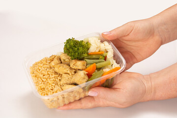 Hand serving healthy chicken packed lunch box meal in front top view clean white background