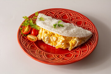 Tapioca Pancake with eggs Brazilian manioc food in top front view red plate clean background