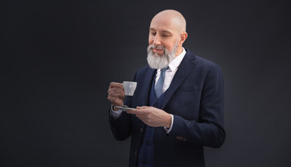 Portrait corporate d'un homme d'affaires qui boit un café debout en souriant sur un fond gris - 762342694