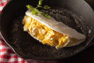 Tapioca Pancake with eggs Brazilian manioc food in top front view inside steel skillet pan