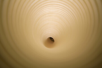 Direct view into a beige paper plastic tunnel creating a hypnotic concentric pattern.