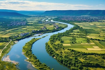 Obraz premium Scenic view of a river flowing through a lush green valley. Perfect for nature and landscape concepts