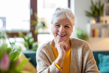 Mature woman looking at camera and smiling in her living room at home
