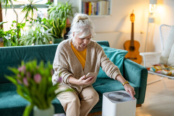 Senior woman using smartphone to set up a home air purifier
- 762350278