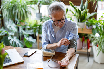 Senior man measuring blood pressure at home
