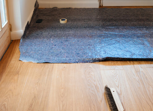 View from above of newly installed parquet flooring, featuring wooden floors covered with gray Malervlies painter's fleece for protection against painting and work.
