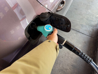 Experience the perspective of a male hand holding the gas pump at the gas station, filling the car...