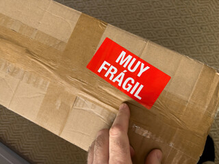 Male hand pointing to the Muy Fragil translated as very fragile from spanish language - cardboard...
