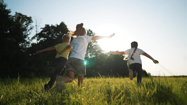 happy family.Kid run and play in meadow in park on green grass.Active recreation for children in nature in summer.Children dream of freedom, outdoor.Children play and run around in park on green grass