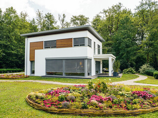 A charming house stands proudly amidst a beautifully designed circular garden, creating a tranquil...