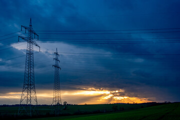 Strommasten und Leitungen am dunklen Wolkenhimmel