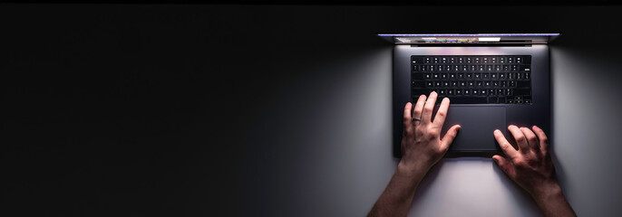 Man using laptop at night, top view, web banner with copy space.