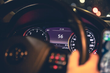 Speed indication and women's hands on the steering wheel in a car at night.