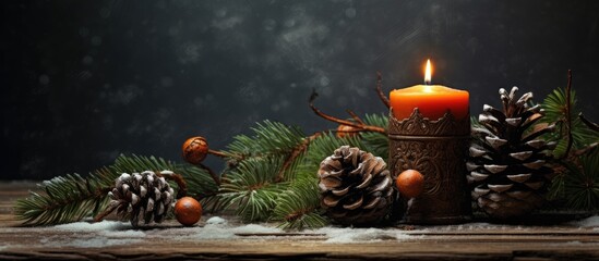 A candle is placed on a wooden table surrounded by pine cones and Christmas decorations, creating a cozy holiday atmosphere