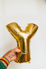 A male hand holds a magnificent golden inflatable helium balloon in the shape of the letter Y. This stunning gold foil balloon font is perfect for invitations, greeting cards, Valentine's Day