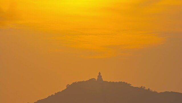 Time Lapse The sun circles behind the Buddha on the mountain as the sun travels from the sky and falls behind the mountain. .The Sky gradually changed color from yellow to orange and red over time.