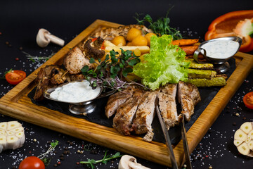 Italian appetizers. Cheese and meat - jamon, salami with olives at wooden serving board at black background. Top view.