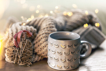 Close-up, shiny gray cup on a blurred background with a knitted element.