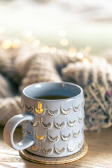 Close-up, shiny gray cup on a blurred background with a knitted element.
