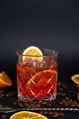 Classic Negroni Cocktail in a retro glass with ice and orange peel on a black background, space for text