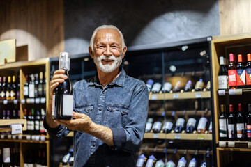 Portrait of a handsome mature man buying wine at a grocery store.
