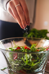 A close up of girl's or woman's hands peeling and cutting vegetables with knife making salad	
