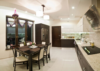 Elegant, modern kitchen inetrior with brown furniture, expensive appliances, illuminated at night....