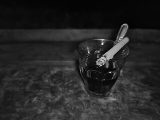 a cigarette on a coffee cup on a wooden table with a black and white background
