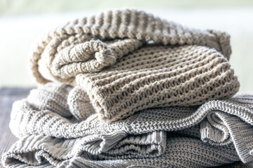 Stack of cozy knitted sweaters on wooden background.
