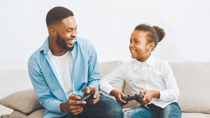 Happy father and daughter playing video game at home