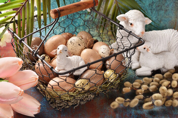Easter background with a wire basket full of eggs, lamb figurines and catkins