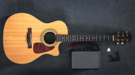 Acoustic guitar and speaker on a black background, top view.