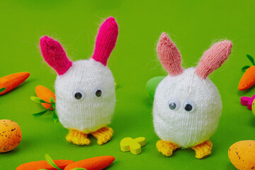 Handmade Easter concept. Knitted bunnies with traditional decoration. Festive symbols, greeting card