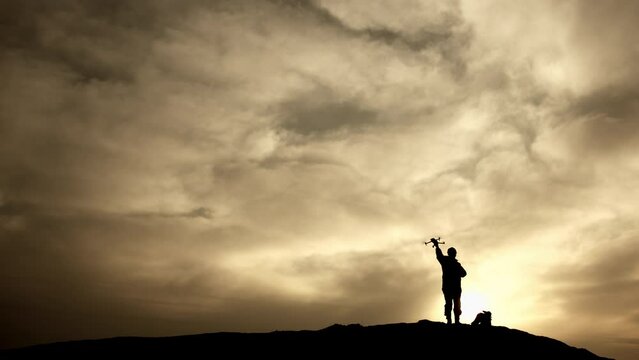 The silhouette of a soldier stands sharply against the fiery backdrop of the setting sun, launching a drone into the twilight sky for strategic reconnaissance. 