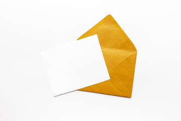 Blank white paper on the golden envelope. Mockup of letter or greeting card. Top view