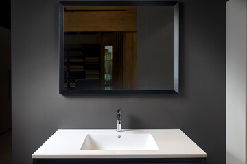 Stoneware countertop bathroom with dark tired beton wall. White industrial flat loft bathroom with modern countertop basin, square mirror and wooden PVC cupboard.