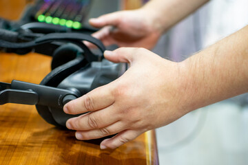 Close up image of hands picking up VR goggles with illuminated keyboard